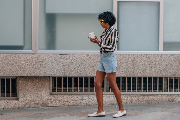 istock woman walking with mobile phone and cup 1872680483