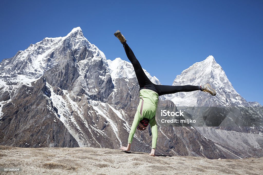 Happy woman celebrates successful climb on Himalayas Female mountaineer celebrates successful climb to the top of the mountain and doing cartwheel. Achievement Stock Photo