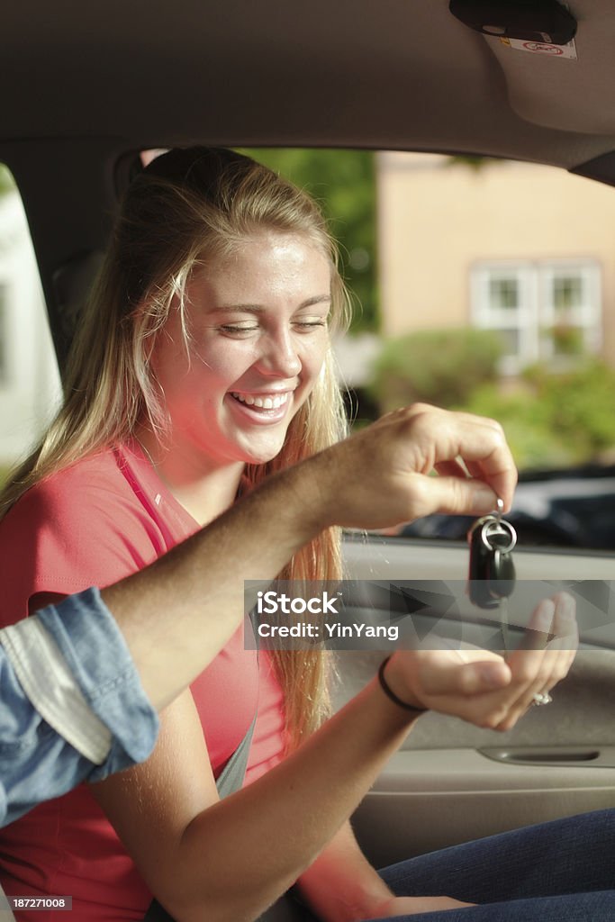 Teen Driver with Her First Car Vertical Subject: A happy young teen receiving car key from parent. Teenager Stock Photo