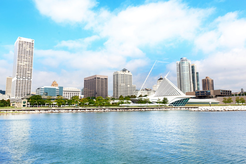 City skyline of Milwaukee, Wisconsin, viewed from Lake Michigan waterfront. Midwest urban architecture includes the famous Milwaukee Art Museum. Summer sky and blue water provide copy space, with no people.