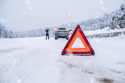 Car accident on a snowy,icy road in winter.Triangle warning sign.