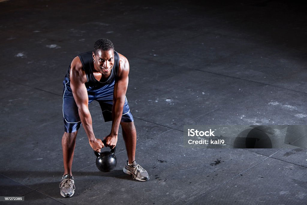 Man working out with kettle bell Young black man (20s) working out with kettle bell weight. Kettlebell Stock Photo