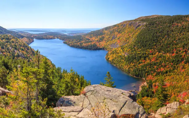 An aerial, stitched panoramic  view of Jordan Pond in Autumn from the top of South Bubble, looking east towards the Atlantic Ocean and the Cranberry Isles. Penobscot Mountain is in the mid-foreground on the right.
