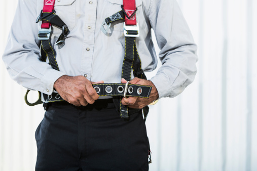 Cropped view of male, African American worker putting on safety harness.