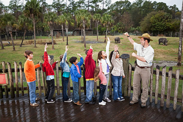 gestore di zoo con gruppo di bambini sul campo viaggio - teaching field trip classroom child foto e immagini stock