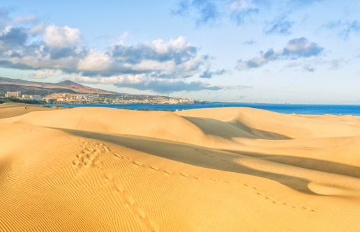 View over the landmark Maspalomas Dunes on Playa de Ingles coastline and peninsula.