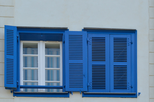 Deux fenêtres sur une façade, l'une avec un volet ouvert, l'autre avec un volet fermé