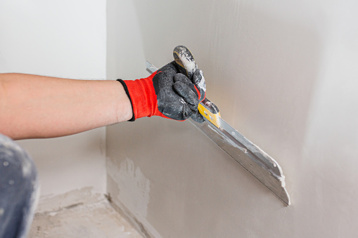 Leveling the wall surface with white putty and a spatula is the work of a qualified painter and finisher