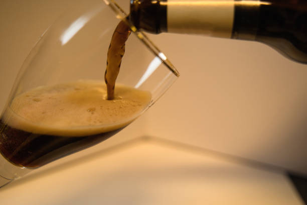 istock Black beer is poured into a glass held at an angle 1872764374