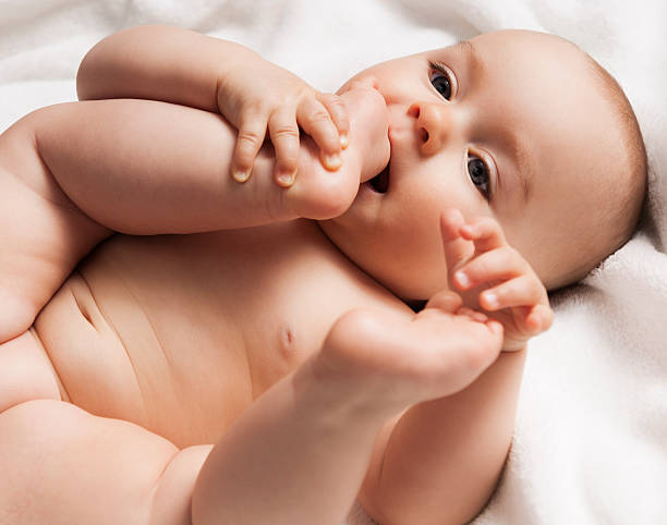 istock 6-7 months old baby child playing with his foot, lying 187276479