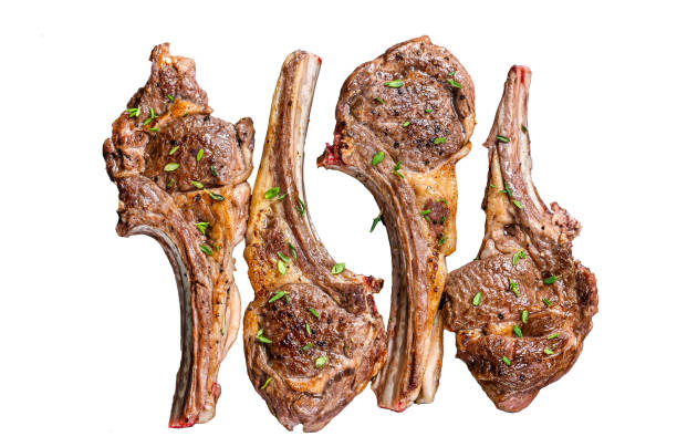 Succulent grilled lamb chops are arranged on a plate, complemented by fresh parsley, a slice of lemon, and a roasted tomato. The dish is perfect for a savory meal.
