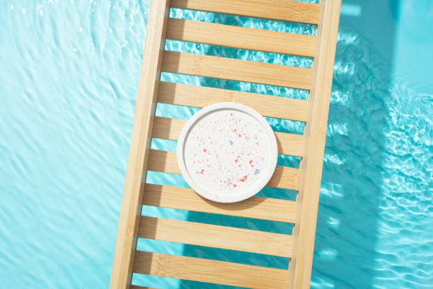 istock Cosmetic product presentation flat lay scene made with empty circle podium on bath tray above the blue water. Template for self-care product placement. 1872780484