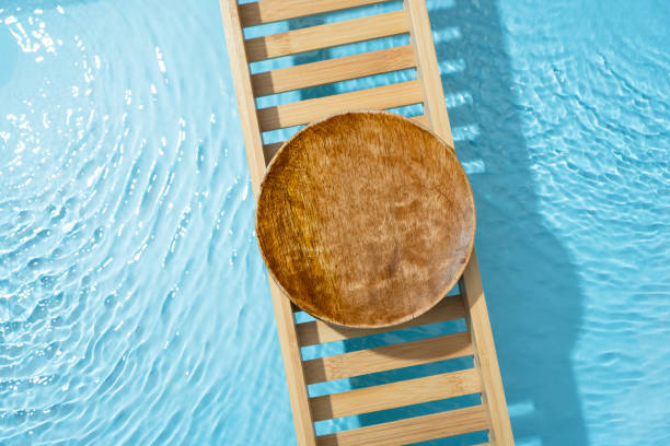 istock Cosmetic product presentation flat lay scene made with empty circle wooden podium on bath tray above the blue water. Template for self-care product placement. 1872780491