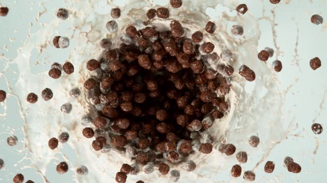 Super slow motion of rotating cereal chocolate pieces with milk splashes.