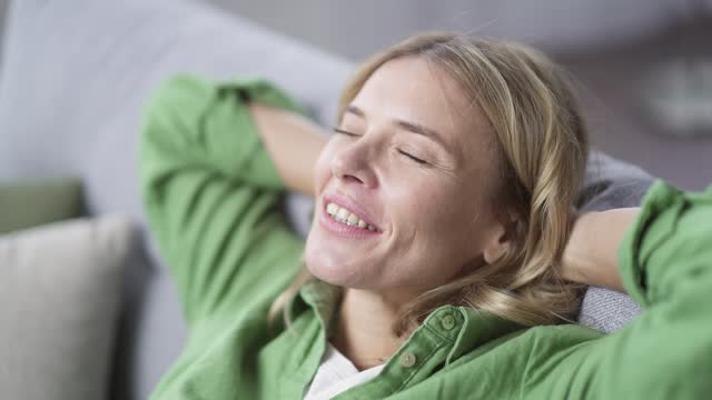 Close-up face of a mature happy woman resting and relaxing satisfied With closed eyes, he inhales deeply and smiles.
