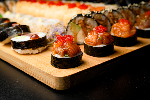 Japanese sushi food. Maki rolls with salmon and tobiko calve. Set of rolls on blurred background.