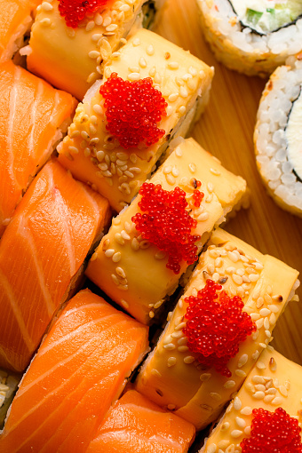Food banner: set of different rolls on a cutting board. Rolls with salmon, cheese, sesame, tobiko calve. Food concept