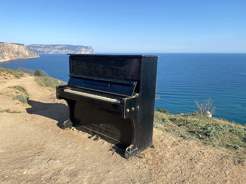 Piano standing on the top of the rock top view to the sea