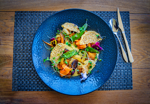 vegetable gnocchi dish in a blue plate on a wooden table