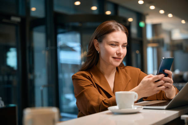 istock Lady sitting at counter and typing something on smartphone 1872876469