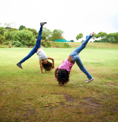 Shot of two young children doing cartwheels in the park