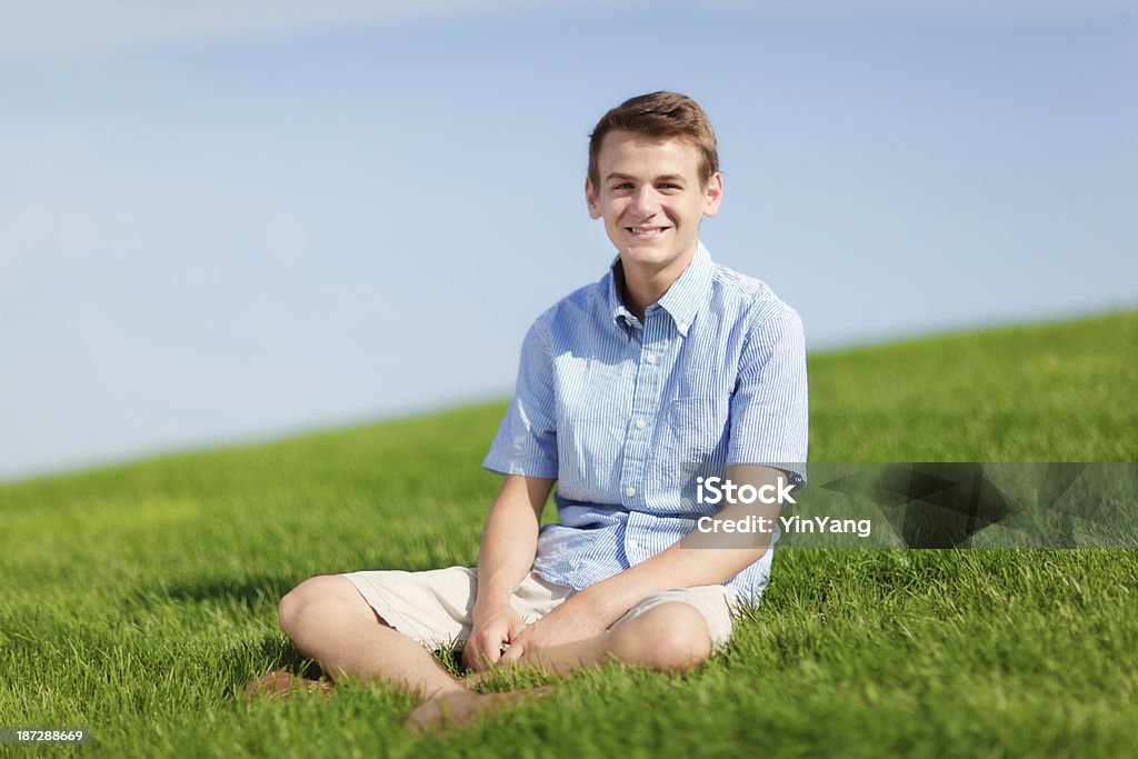 Feliz, sorrindo jovem sentado ao ar livre na grama Meadow Slope - Foto de stock de Anarruga royalty-free