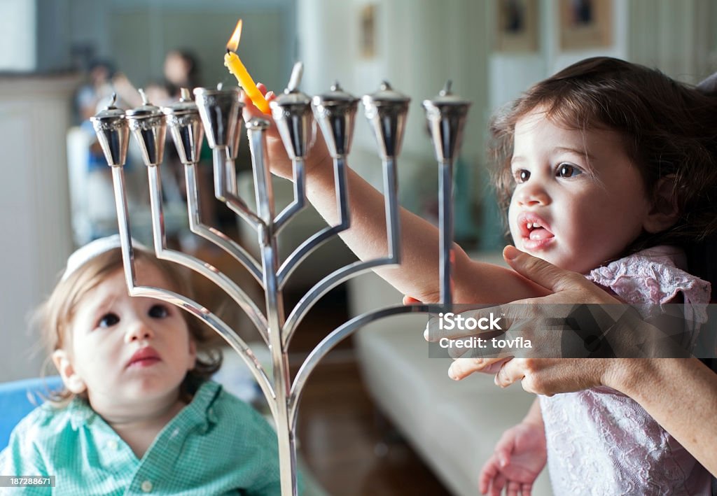 Young girl lights the Hanukkah menorah with help from adult Lighting  the Hanukkah Menorah Hanukkah Stock Photo