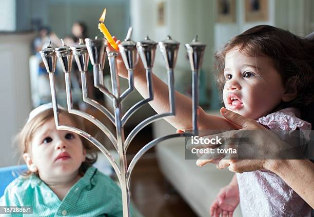 Young Girl Lights The Hanukkah Menorah With Help From Adult Stock Photo - Download Image Now