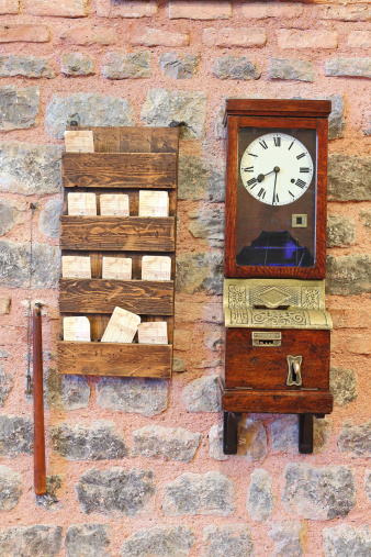 Old time clock at a work place together with time card holding shelves.