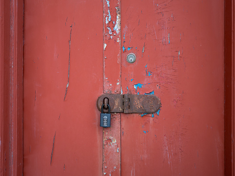 21 December 2023. Lossiemouth,Moray,Scotland. This is a red doorway to an old pub which is padlocked closed with a chubb, yale and squire lock.