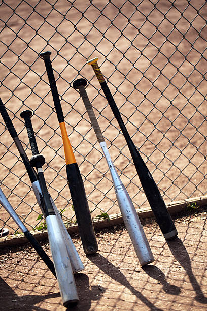 istock Baseball bats lean against chain link fence during game. 187290729