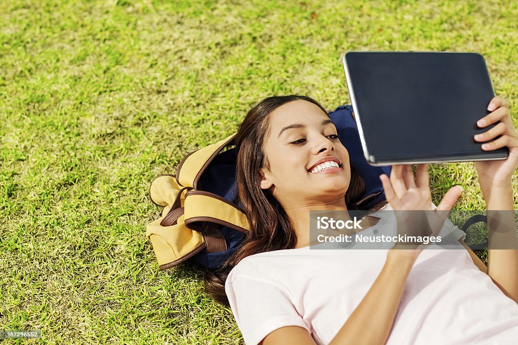 여자아이 디지털 태�블릿 라잉 On 잔디 At 캡퍼스 - 로열티 프리 16-17 살 스톡 사진