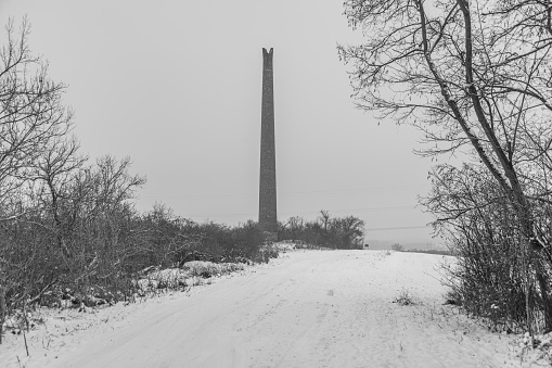 Rana hill in white storm snowy morning near Louny town with old ruin chimney