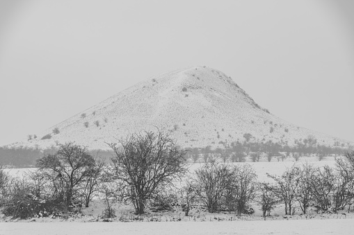 Rana hill in white storm snowy morning near Louny town and cold meadows