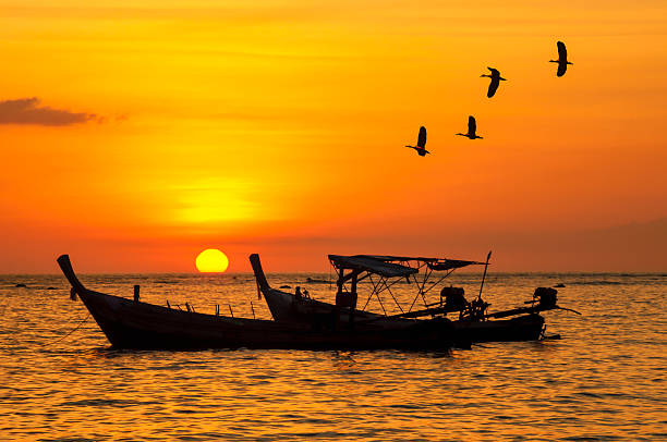 istock Small fishing boat with birds and sunsets 187300525