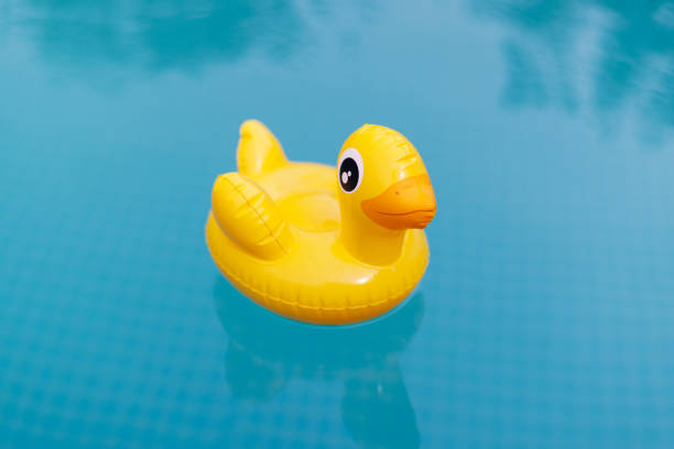 istock Yellow inflatable duck floating on blue water in a pool on a hot summer day 1873018355