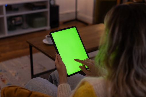 Shot of a unrecognizable woman using her tablet at home