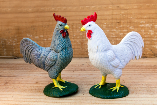 Toy white and gray roosters. Vertical.