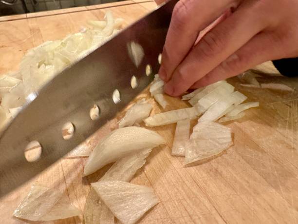 istock Cutting onions on wooden cutting board 1873044262