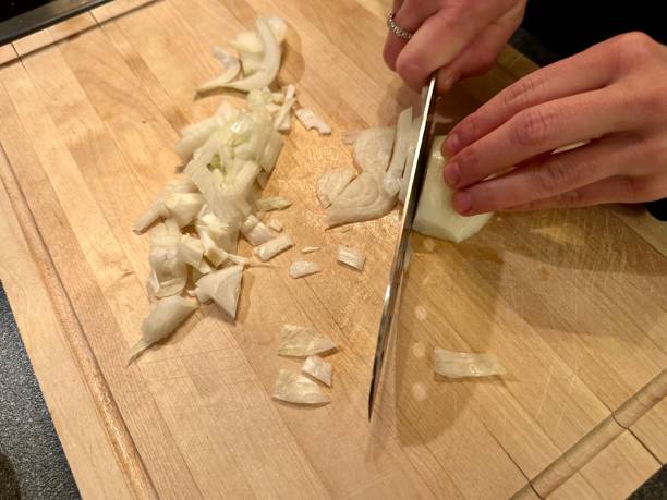 istock Cutting onions on wooden cutting board 1873044273