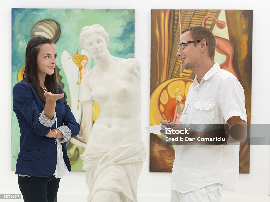 understanding the artwork two young caucasian people talking about a sculpture and taking notes in a museum Adult Stock Photo