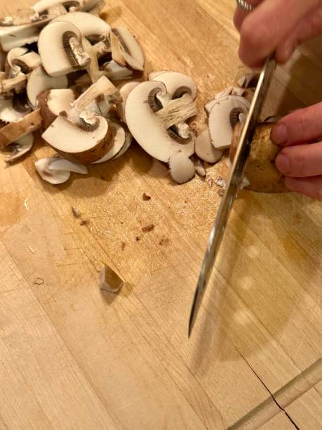 istock Cutting mushrooms to slices on wooden curring board 1873053519