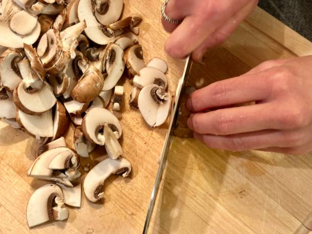 istock Cutting mushrooms to slices on wooden curring board 1873054034