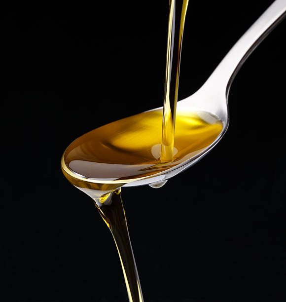 Olive Oile Poured Olive Oil Poured from a bottle to a spoon isolated on black olive oil pouring antioxidant liquid stock pictures, royalty-free photos & images