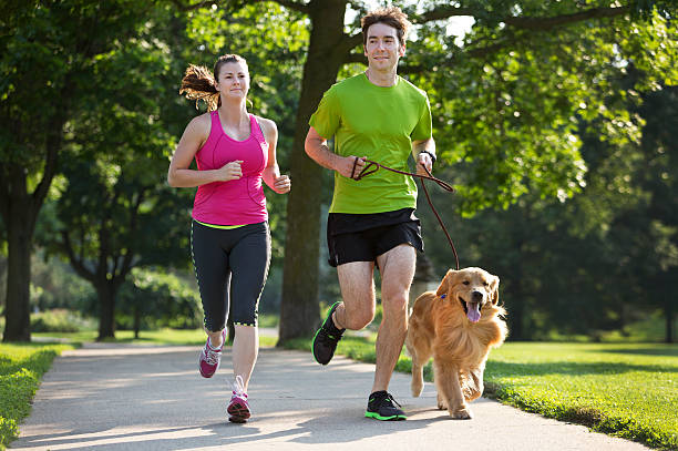 istock Golden Retriever , Man and Woman Jogging on a Paved Path. 187306932