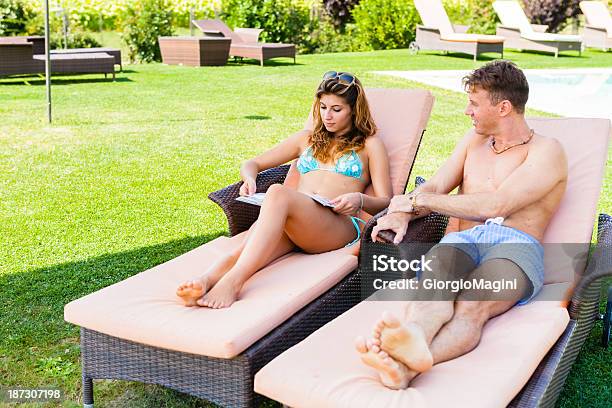 Photo libre de droit de Jeune Couple De Détente Au Bord De La Piscine Pendant Les Vacances banque d'images et plus d'images libres de droit de Lire