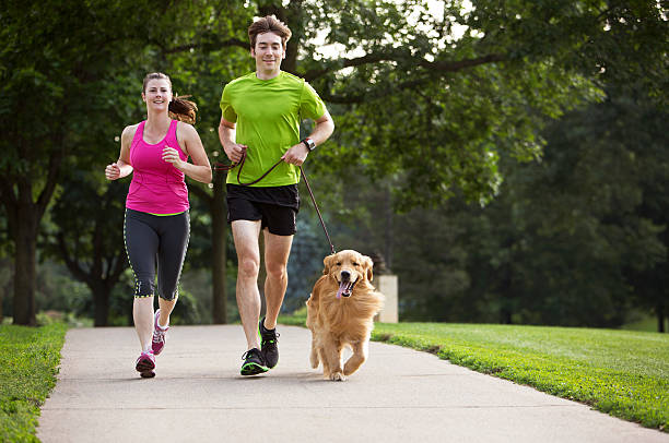 istock Golden Retriever , Man and Woman Jogging on a Paved Path. 187307666