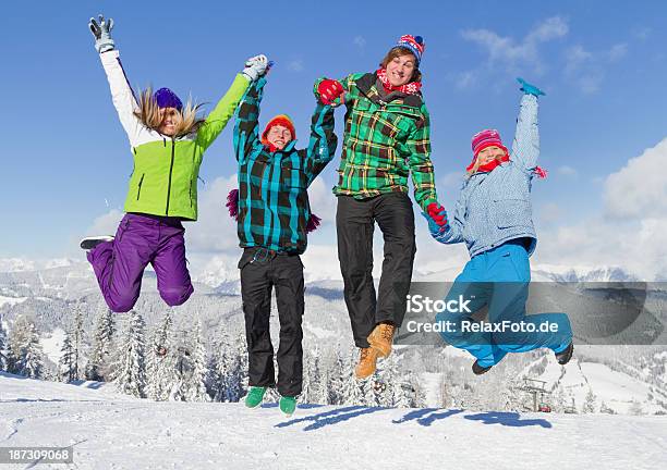 Photo libre de droit de Quatre Jeunes Gens En Vêtements Dhiver De Sauter Dans La Neige banque d'images et plus d'images libres de droit de Activités après le ski