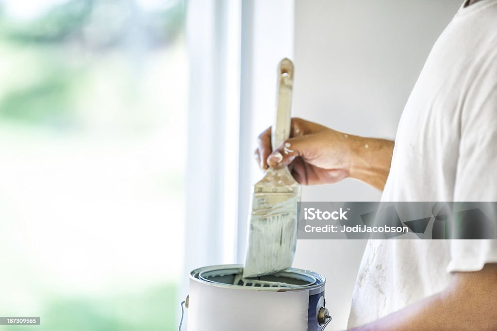Painter dipping his brush in paint can A house painter dips his brush into a can of paint.  rr House Painter Stock Photo