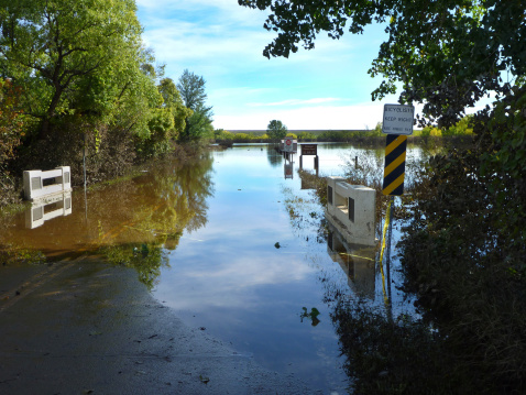 Just east of the town of Morrison, a submerged road and signs emerge after flood waters recede from Bear Creek which inundated Lakewood, Colorado's Bear Creek Lake Park after days of heavy mid-September rains. The reservoir dam and muddy trees stand in the distance.